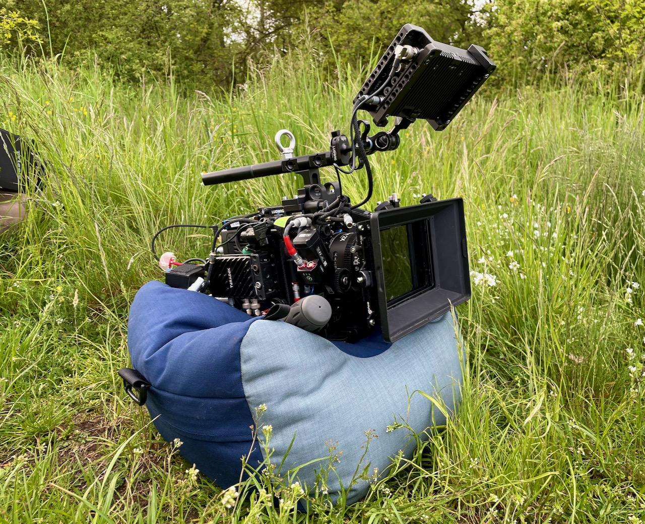 Kamerakissen von kirschpack in Blau und Hellgrau als Auflage für eine Filmkamera im Gras