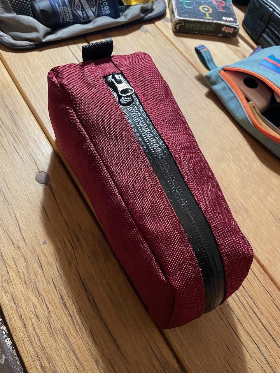 Oberrohrtasche von kirschpack in Weinrot mit schwarzem Reißverschluss auf einem Holztisch