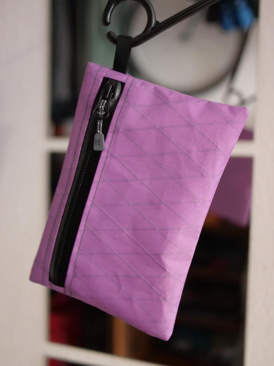 Zipperbag 13×18 von kirschpack in Flieder aus X-Pac, an einem Haken hängend