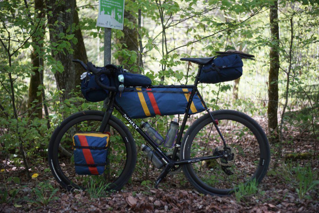 Gravelbike im Wald mit Rahmentasche, Satteltasche und Lenkerrolle von kirschpack