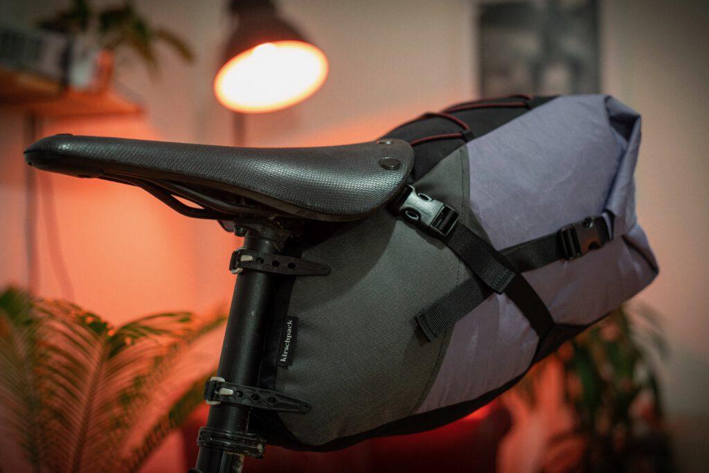 Satteltasche »Arschrakete« von kirschpack in Grau und Violett am Sattel im warmen Licht