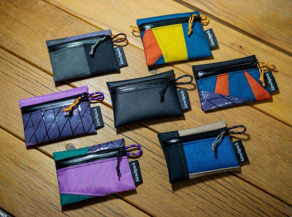 Auswahl an Trail Wallets von kirschpack in Schwarz, Blau, Violett und Gelb auf einem Holztisch