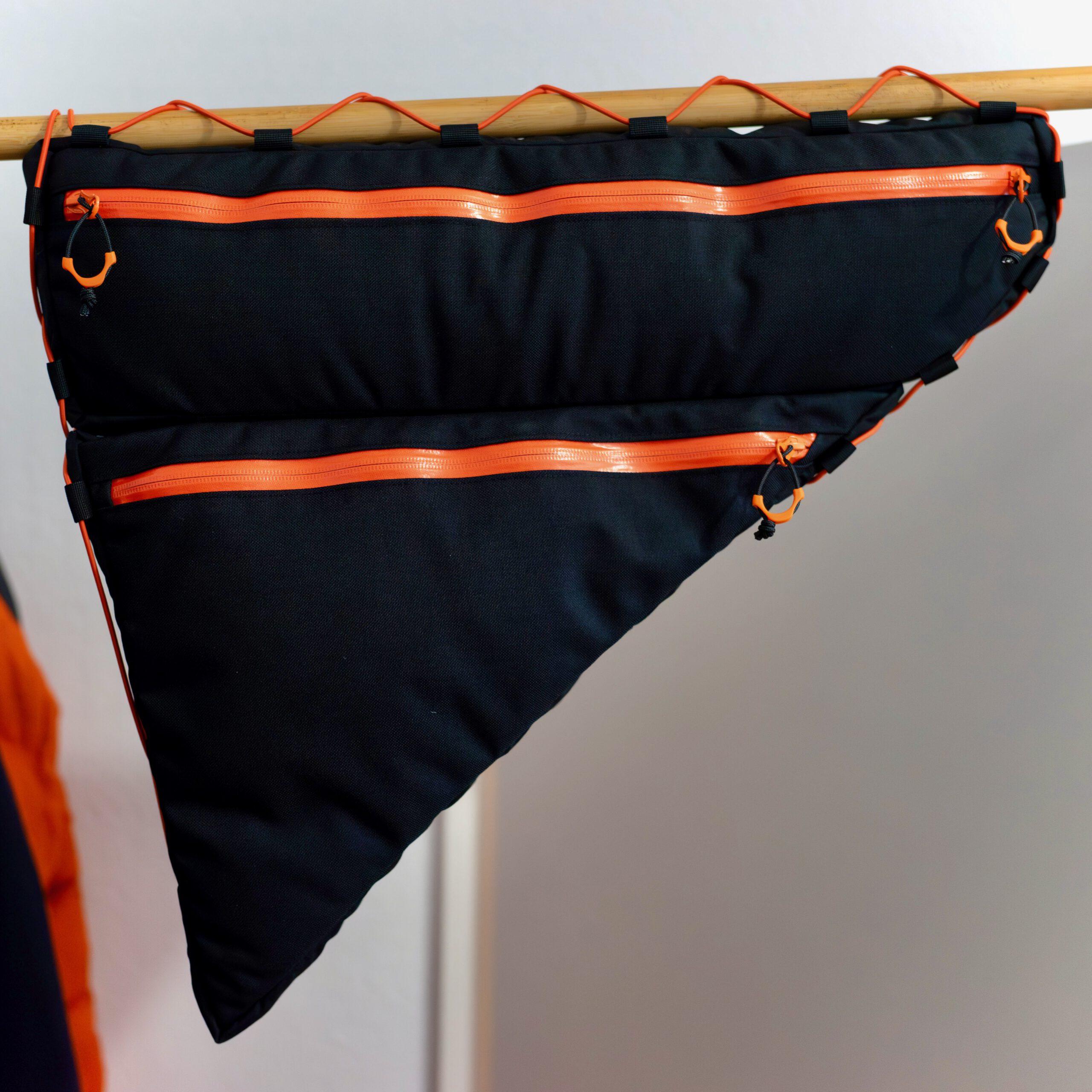 Rahmentasche fullframe 2-teilig von kirschpack, in Schwarz mit orangefarbenen Reißverschlüssen an einer Holzstange hängend