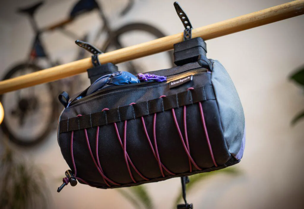 Lenkerrolle Zipper von kirschpack in Schwarz mit violettem Gummizug, hängend an einer Stange, Frontansicht