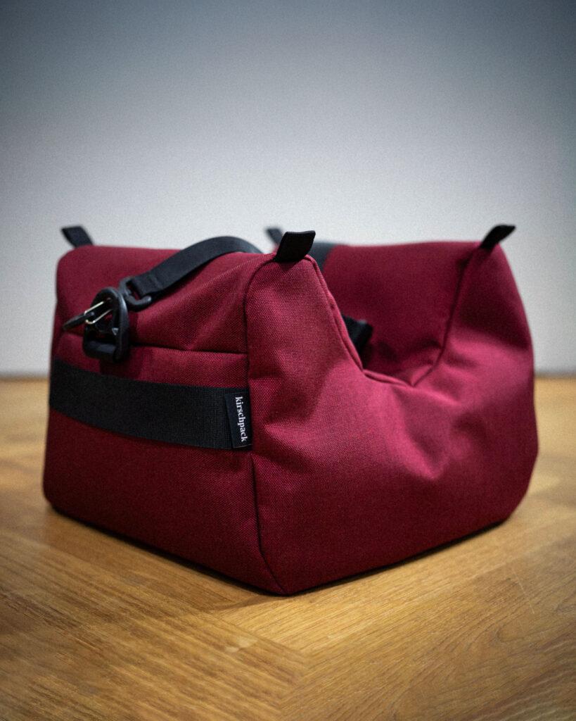 Kamerakissen Mini von kirschpack in Weinrot, Gesamtansicht auf Holzboden